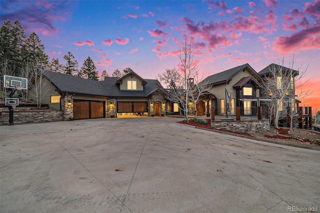 view of front of home featuring curved driveway, an attached garage, and stone siding