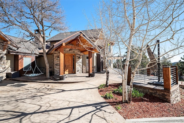 view of front of house with roof with shingles, fence, and stone siding