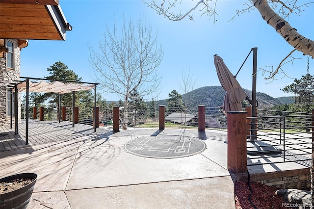 view of patio / terrace with a pergola, fence, and a mountain view