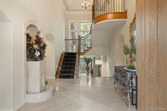 foyer entrance with crown molding, a notable chandelier, and a high ceiling