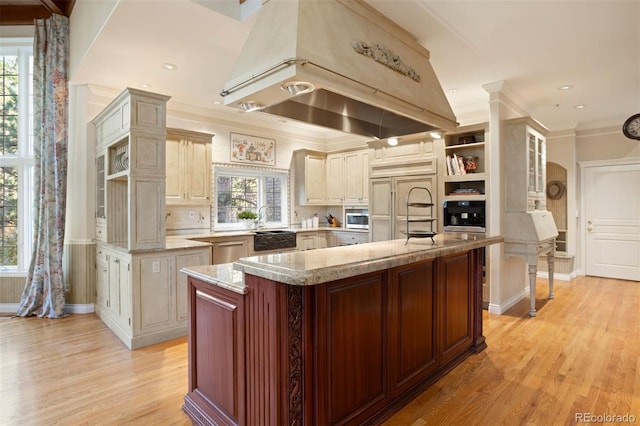 kitchen with appliances with stainless steel finishes, a healthy amount of sunlight, island range hood, and a kitchen island