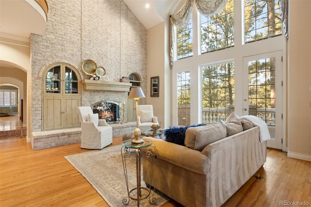 living room featuring crown molding, high vaulted ceiling, a fireplace, and hardwood / wood-style floors