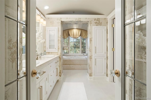 bathroom with vanity, ornamental molding, a relaxing tiled tub, and tile patterned floors