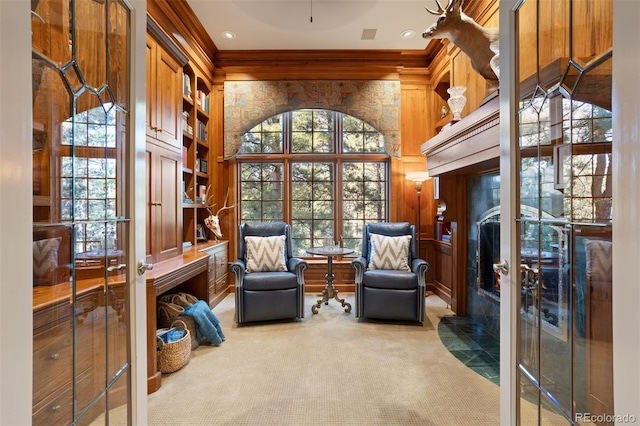 sitting room with wooden walls, carpet flooring, and a healthy amount of sunlight