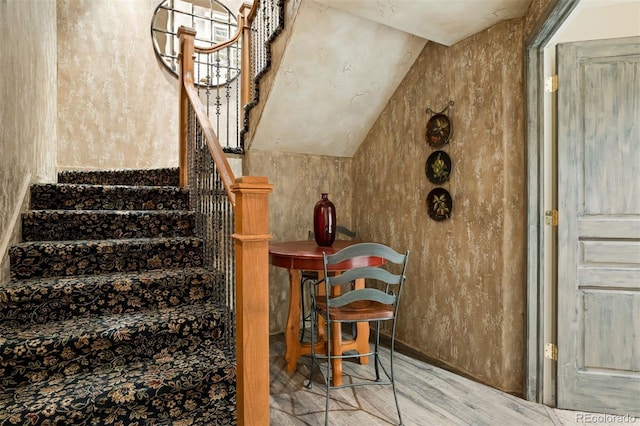 stairway featuring wood-type flooring and lofted ceiling