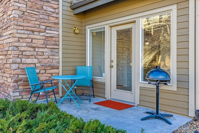 doorway to property featuring stone siding and a patio