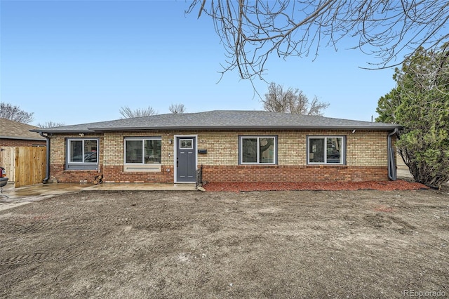 ranch-style house featuring fence, brick siding, and roof with shingles