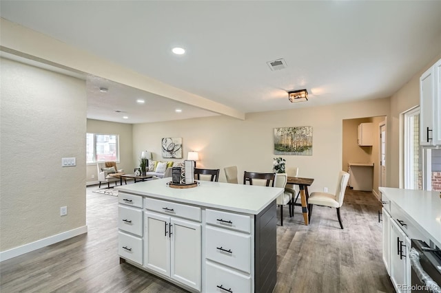 kitchen featuring light countertops, wood finished floors, visible vents, and a center island