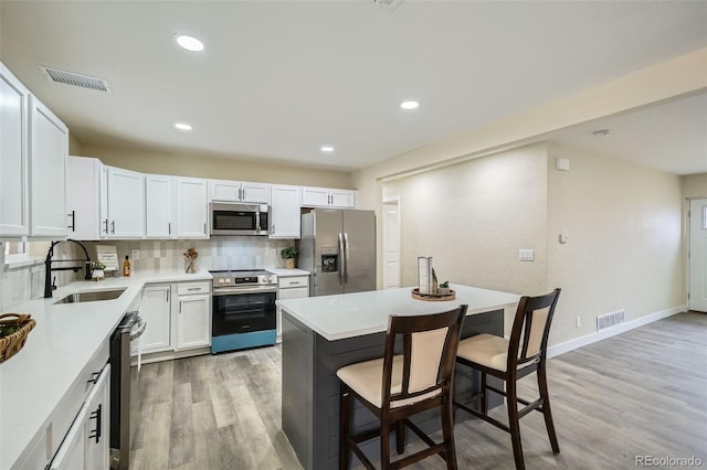 kitchen with tasteful backsplash, visible vents, appliances with stainless steel finishes, a sink, and a kitchen breakfast bar