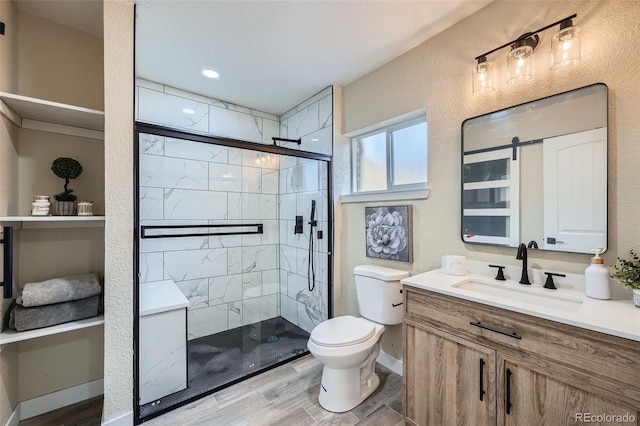 full bath featuring a stall shower, a textured wall, toilet, wood finished floors, and vanity