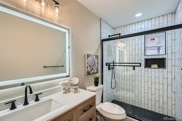 full bath featuring a textured wall, a tile shower, toilet, and vanity