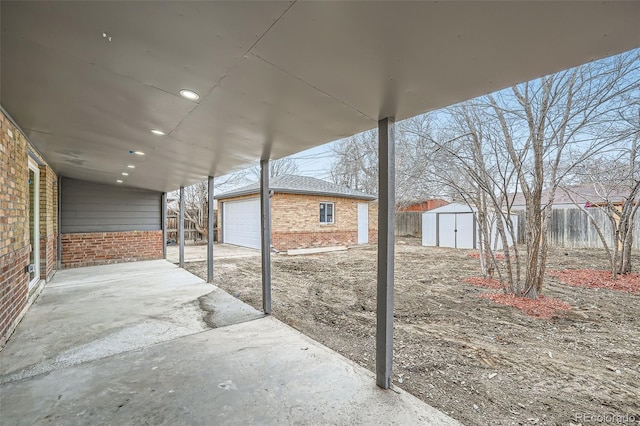 view of patio / terrace featuring a garage, an outbuilding, and fence