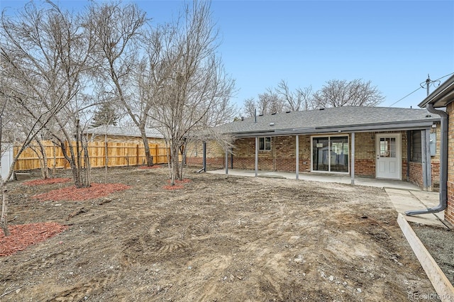 back of property featuring a shingled roof, fence, a patio, and brick siding