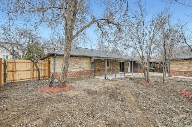 back of property with a shingled roof, fence, a patio, and brick siding