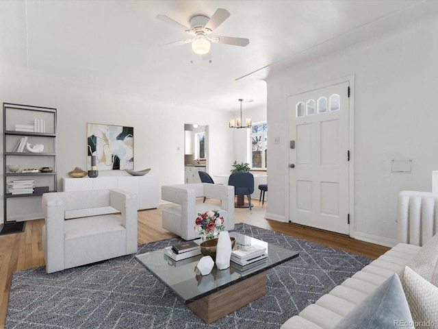 living room with ceiling fan with notable chandelier and dark wood-type flooring