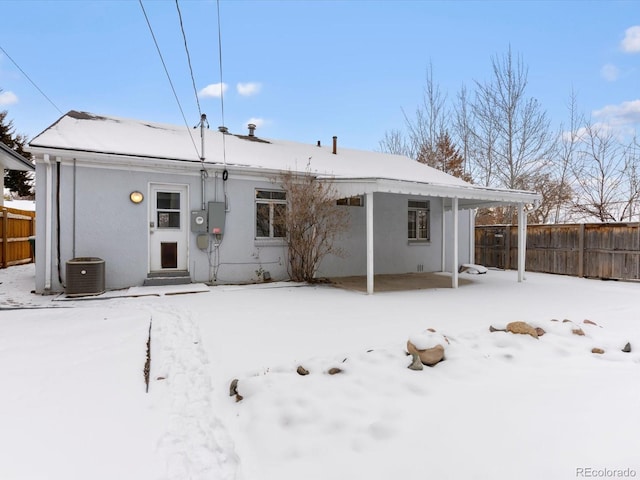 snow covered back of property featuring central air condition unit