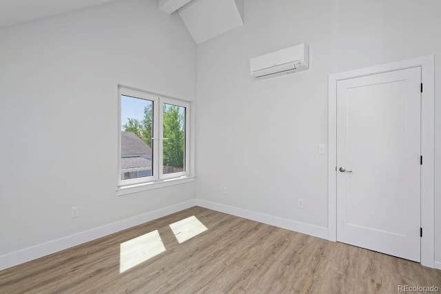 empty room featuring light hardwood / wood-style floors, high vaulted ceiling, and a wall unit AC