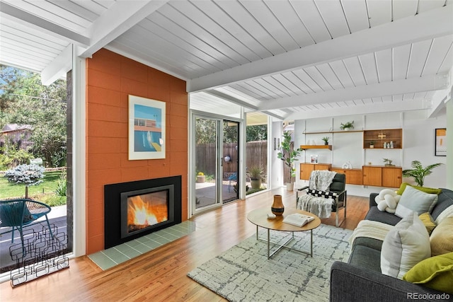 1338 S Fairfax St, Denver, CO 80222 - living area featuring floor to ceiling windows, beamed ceiling, wood finished floors, and a tiled fireplace
