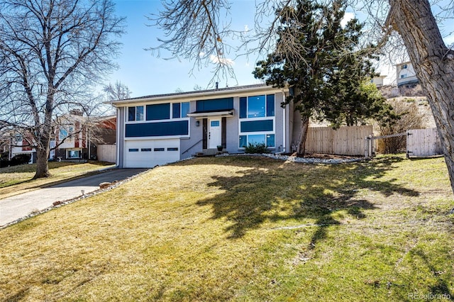 split foyer home with aphalt driveway, an attached garage, a front lawn, and fence