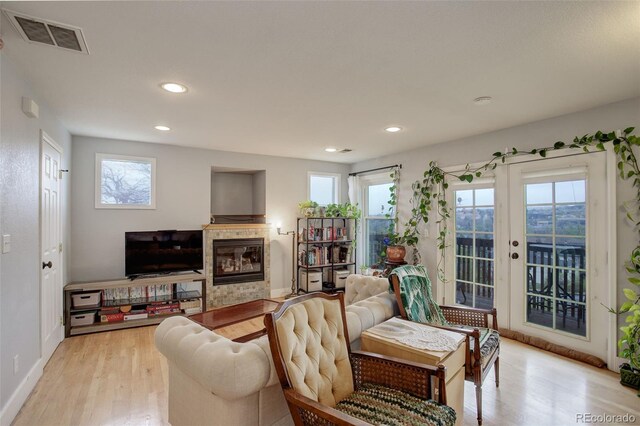 living room with a tiled fireplace, light wood-style flooring, recessed lighting, and baseboards