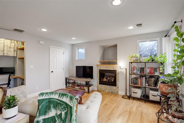 living room featuring a tile fireplace, baseboards, recessed lighting, and wood finished floors