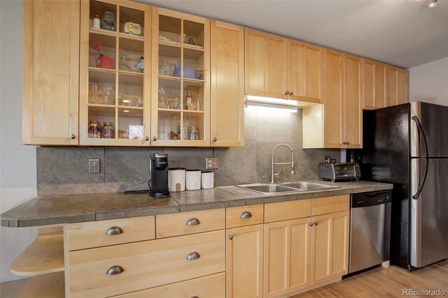 kitchen with appliances with stainless steel finishes, light brown cabinets, a sink, and backsplash