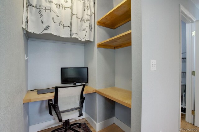 office area featuring wood finished floors, baseboards, a textured wall, and built in study area