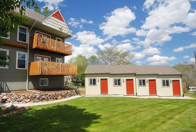 back of house with a balcony and a lawn