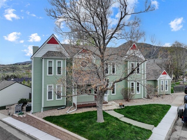 victorian home with central AC, a front yard, and a chimney