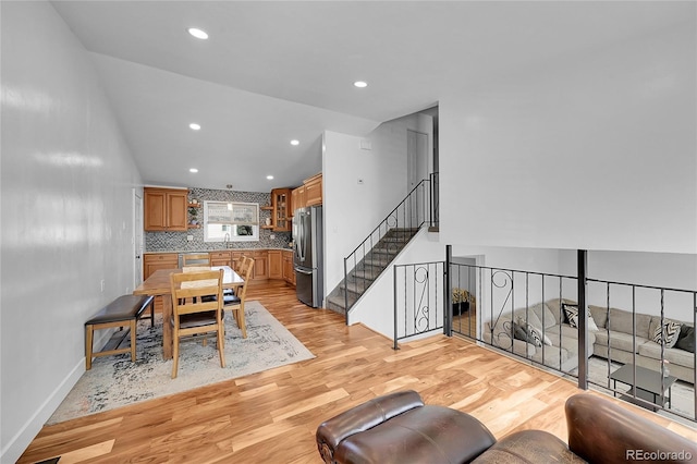 dining room with sink, lofted ceiling, and light wood-type flooring