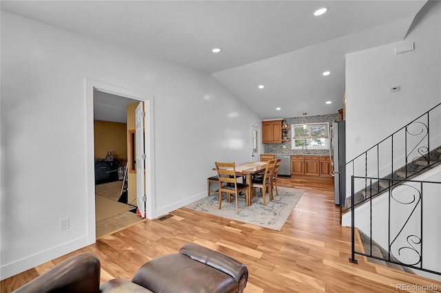 dining area with sink, light hardwood / wood-style flooring, and lofted ceiling