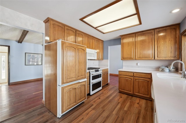 kitchen with beamed ceiling, double oven range, sink, and dark hardwood / wood-style floors