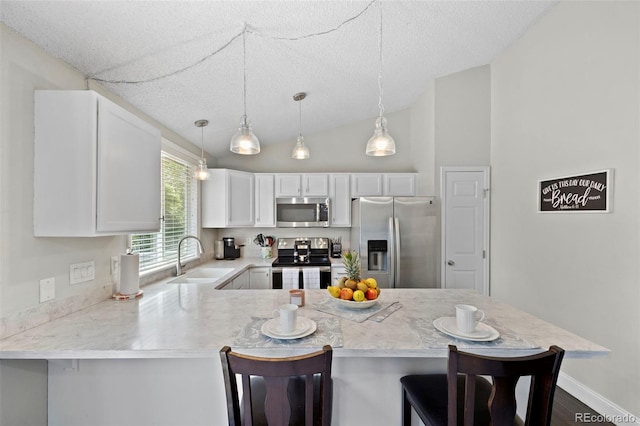 3965 S Fundy Cir, Aurora, CO 80013 - kitchen featuring appliances with stainless steel finishes, a peninsula, a breakfast bar, vaulted ceiling, and white cabinetry