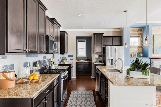 kitchen with pendant lighting, sink, appliances with stainless steel finishes, backsplash, and light stone countertops