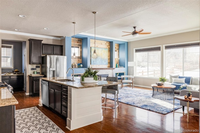 kitchen with sink, light stone counters, dark hardwood / wood-style floors, pendant lighting, and stainless steel appliances