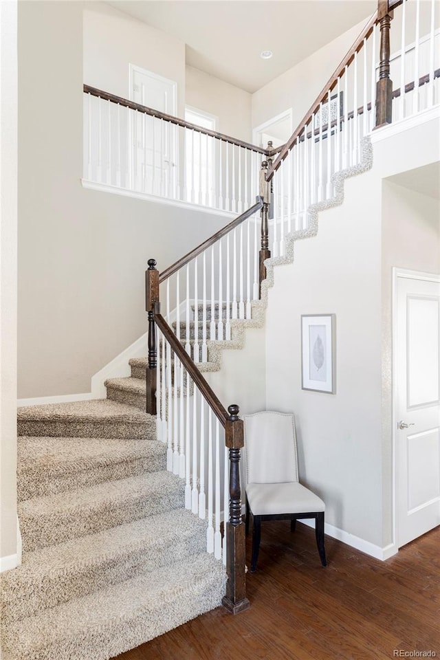 staircase featuring hardwood / wood-style flooring and a high ceiling