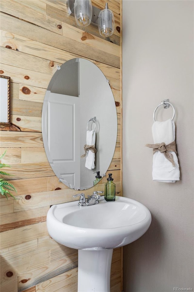 bathroom featuring sink and wooden walls