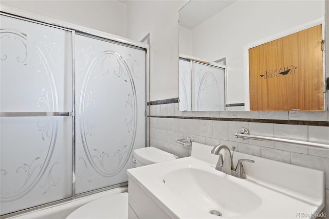 5960 Glencoe St, Commerce City, CO 80022 - bathroom with toilet, tile walls, vanity, bath / shower combo with glass door, and a wainscoted wall