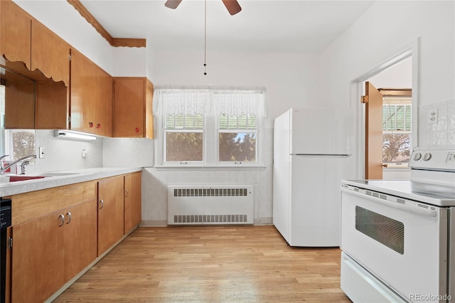 5960 Glencoe St, Commerce City, CO 80022 - kitchen with radiator heating unit, white appliances, a sink, light wood-type flooring, and light countertops