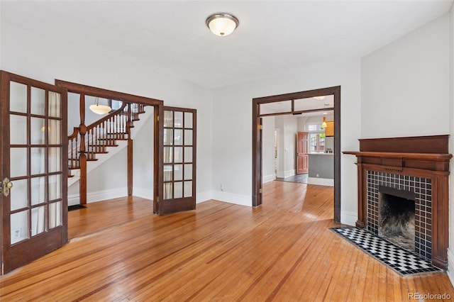 1352 N Downing St, Denver, CO 80218 - unfurnished living room with french doors, stairway, wood-type flooring, and a tile fireplace