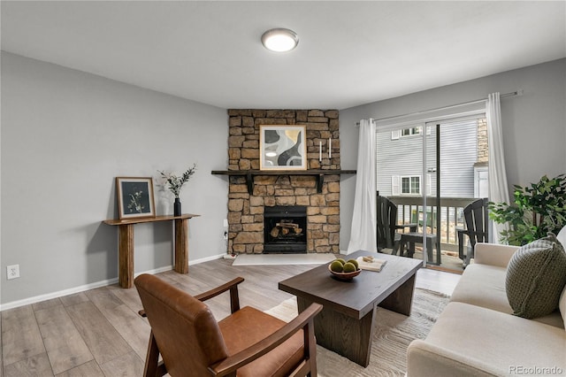 living room with a fireplace, light wood-type flooring, and baseboards