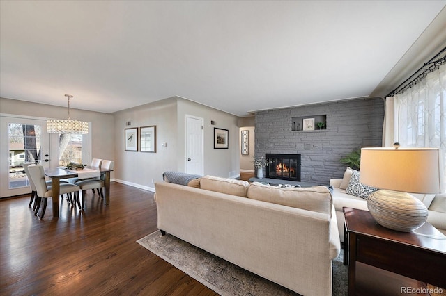 living room with a notable chandelier, dark hardwood / wood-style floors, and a fireplace