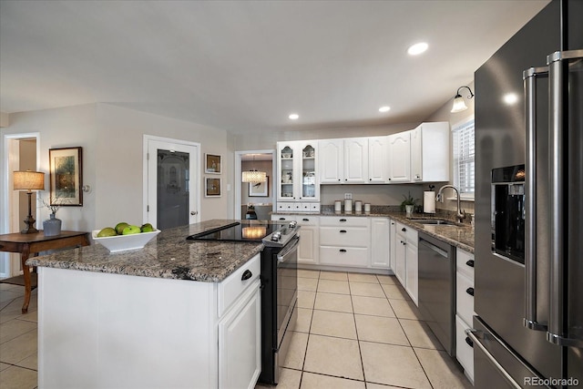 kitchen featuring dishwashing machine, white cabinetry, high end fridge, a kitchen island, and range with electric cooktop