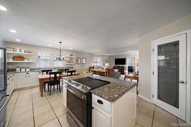 kitchen with pendant lighting, white cabinetry, dark stone counters, light tile patterned floors, and stainless steel electric range