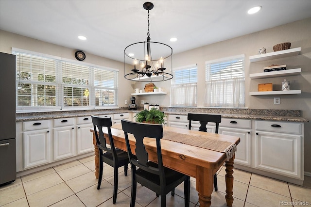 kitchen featuring refrigerator, white cabinetry, light tile patterned floors, decorative light fixtures, and an inviting chandelier