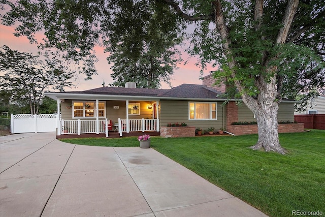 ranch-style home with covered porch and a yard