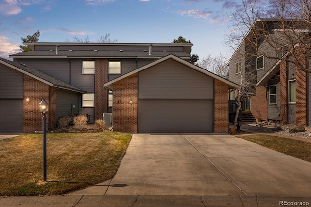 view of front of house with central air condition unit, driveway, a front lawn, an attached garage, and brick siding