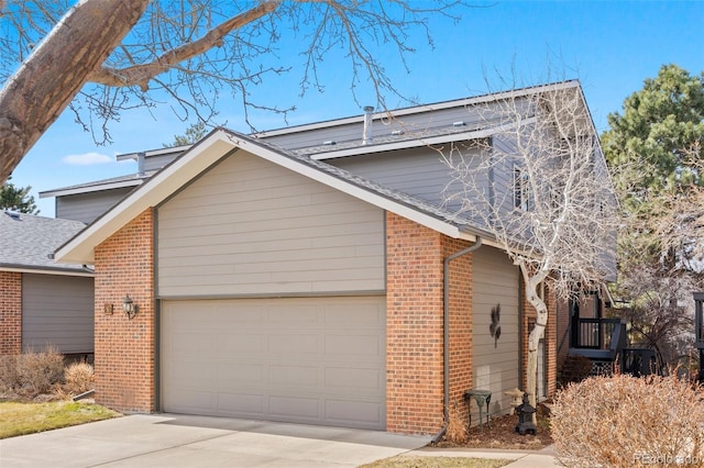 view of side of property featuring an attached garage, brick siding, and driveway