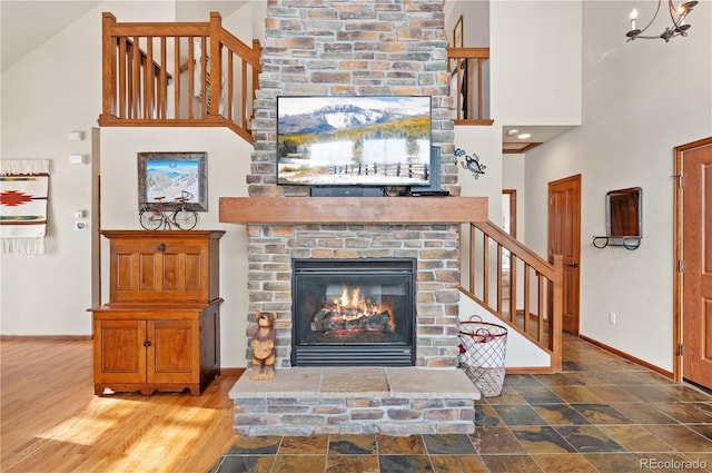 living room featuring a fireplace, hardwood / wood-style floors, a chandelier, and a high ceiling