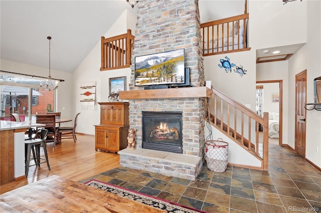 living room with a fireplace, an inviting chandelier, hardwood / wood-style flooring, and high vaulted ceiling